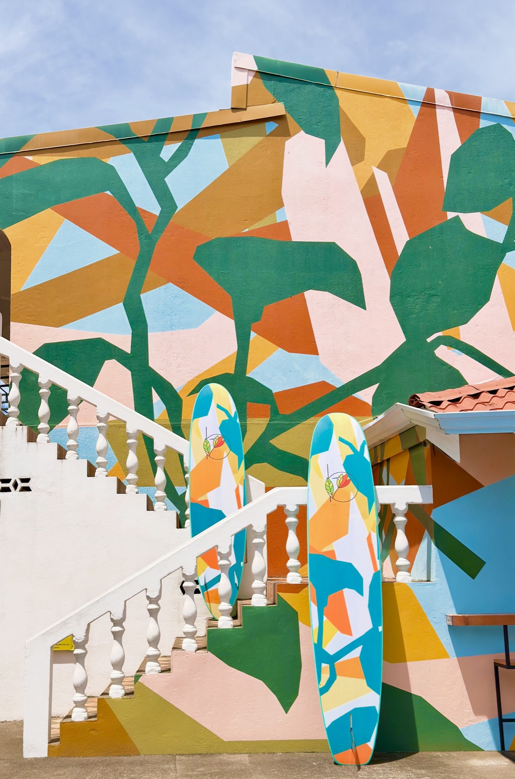 Surfboards painted to match the stairwell mural, standing against it at Bird of Paradise Hotel in Jacó